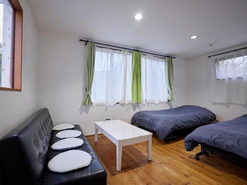 a room with two beds and a couch and a table at Casa Allegra in Yamanakako