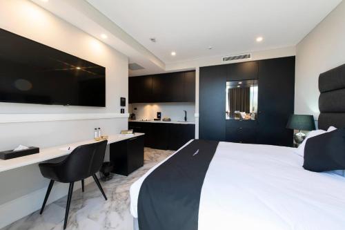 a bedroom with a bed and a desk and a tv at Gladius Hotels & Suites Parramatta, an Ascend Hotel Collection in Parramatta