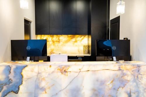 a marble desk with two monitors and two computer screens at Gladius Hotels & Suites Parramatta, an Ascend Hotel Collection in Parramatta