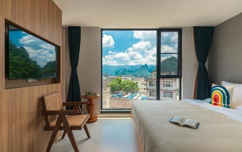 a bedroom with a large window with a bed and a chair at Yangshuo MUSE Mountain View Retreat in Guilin