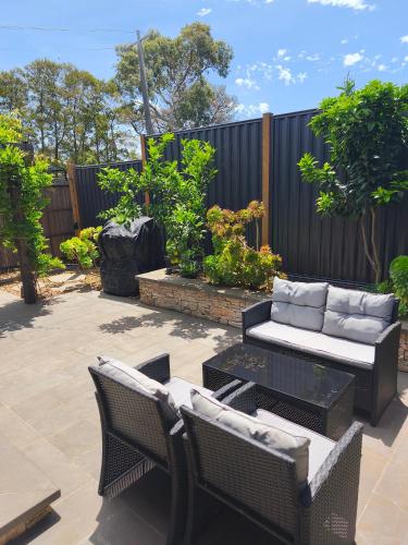 a patio with two wicker chairs and a couch at Tiny House Experience in Sunset Strip
