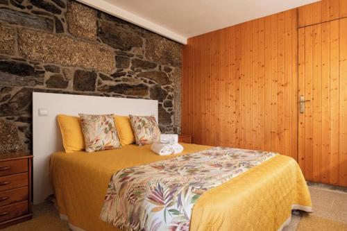 a bedroom with a bed and a stone wall at Quinta da Raiz in Canedo de Basto