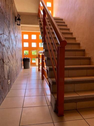 a hallway with stairs in a building with an orange door at Suites Posada Obregon in Ciudad Obregón
