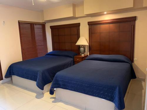 two beds in a bedroom with blue comforter at Suites Posada Obregon in Ciudad Obregón