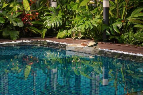 a swimming pool in a garden with green plants at GRAND CITITEL Hanoi Hotel & Spa in Hanoi