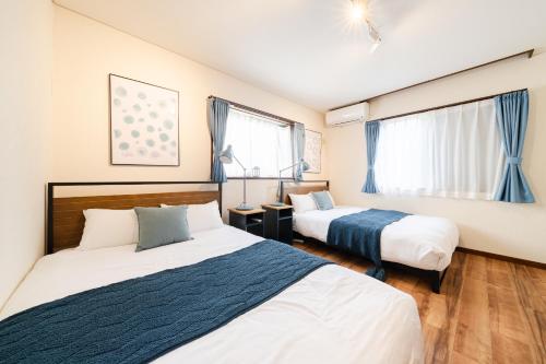 a bedroom with two beds and two windows at HOTEL AndPlace ShinOkubo in Tokyo