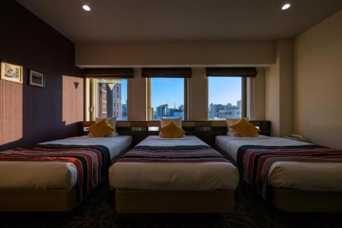 a room with three beds in a room with windows at HOTEL MYSTAYS Ueno East in Tokyo
