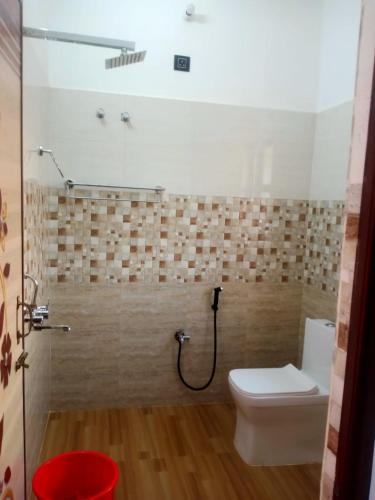 a bathroom with a toilet and a shower with a hose at The Palindrome in Guwahati