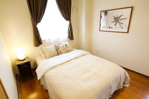 a bedroom with a white bed and a window at カラハーイもとぶ 2-3 in Motobu