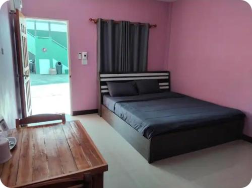 a bedroom with a bed and a wooden table at K and K Resort room 1 in Prakhon Chai