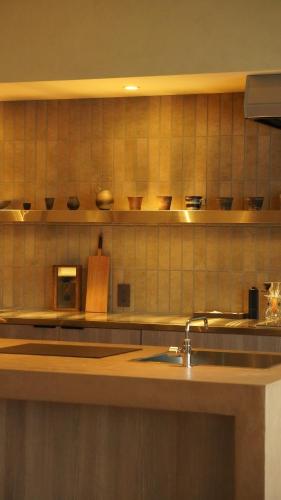 a kitchen with a sink and shelves with bowls on the wall at 雲居月-kumoizuki- in Ginowan