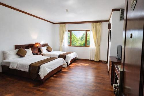 a hotel room with two beds and a flat screen tv at EG Paradise Angkor Villa Hotel in Siem Reap