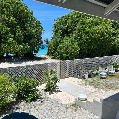 a backyard with a fence and chairs and the beach at LE FARE BLEU Chambres d'hôtes climatisées en bord de lagon à Tiputa Rangiroa - vélos gratuits et snorkeling in Tiputa