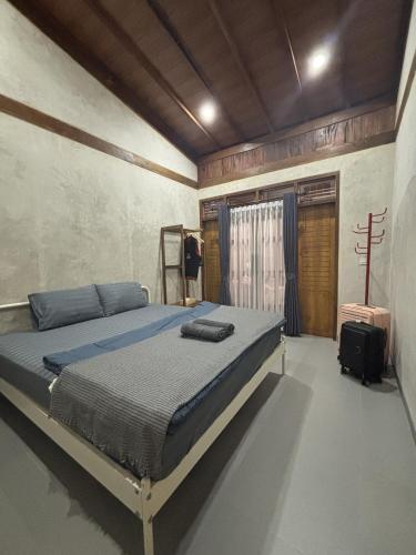 a bedroom with a bed and a suitcase in it at Pam's Cabin Batukaras in Batukaras