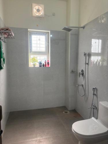 a bathroom with a shower and a toilet and a window at Deepalaya in Guwahati