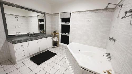 a white bathroom with a tub and a sink at Kalani - The Heavens View House in Freshwater
