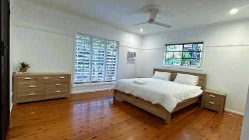 a bedroom with a bed and two windows at Kalani - The Heavens View House in Freshwater