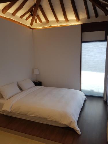 a bedroom with a white bed and a large window at Andong Hanok Stay Hue in Andong