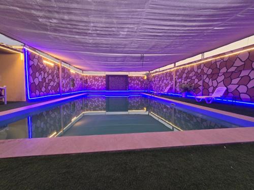 a indoor swimming pool with purple lights on the walls at NMY Farm1 in Ras al Khaimah