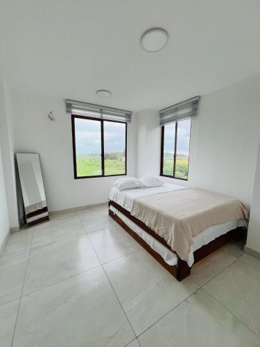 a white bedroom with a large bed and windows at Cesar Palace Departamento in Cojimíes
