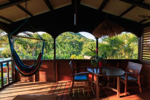 a porch with a hammock and a table and chairs at Piton Bungalows Ecolodges in Deshaies