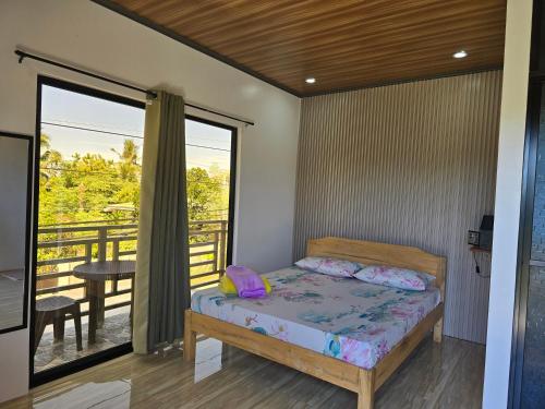 a bedroom with a bed and a balcony at Mollucan Suite Moalboal in Moalboal