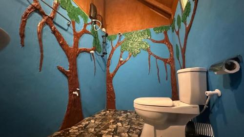 a bathroom with a mural of trees on the wall at Sigiri Aliya Tree house in Sigiriya