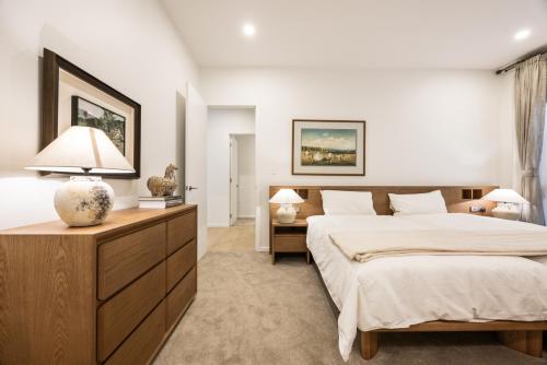 a bedroom with a large bed and a dresser at Shining House Villa B in Tanunda