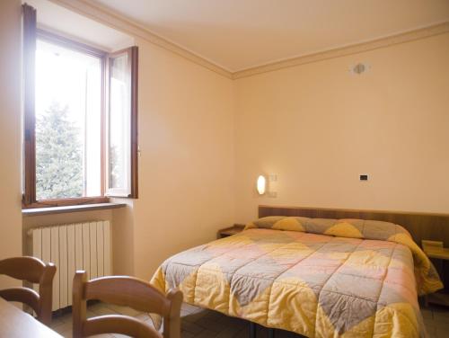 sypialnia z łóżkiem i oknem w obiekcie Hotel Fontemaggio w Asyżu