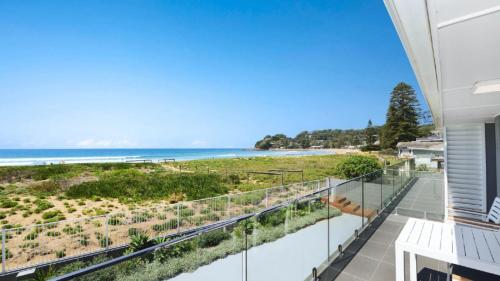 a balcony with a view of the beach at Pacific Court 'absolute Beachfront=' in Avoca Beach