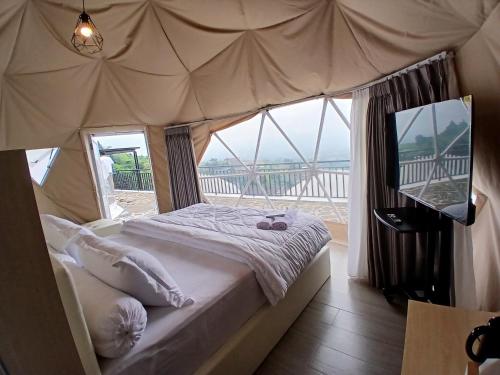 a bedroom with a bed and a large window at Anemos Resort By Tamastu in Pasirpogor