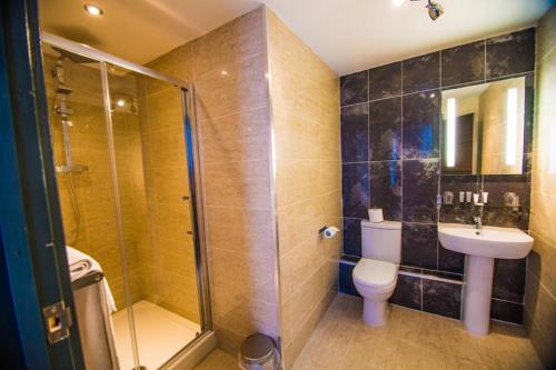 a bathroom with a shower and a toilet and a sink at The Grand Hotel in Swansea