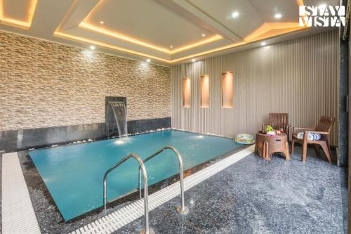 a large swimming pool in a room with a table and chairs at StayVista at The Binclave with Jacuzzi, Pvt Indoor Pool, Bar & Projector in Jaipur