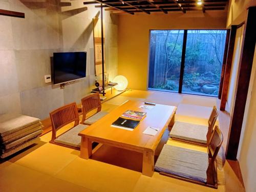 a living room with a table and chairs and a television at Zen Machiya Private Residence near Heian Shrine in Kyoto
