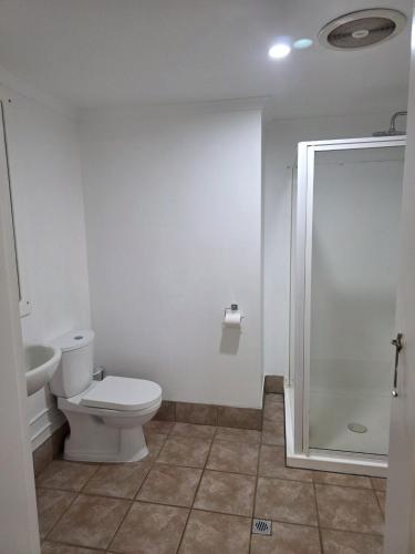a white bathroom with a toilet and a shower at Tranquility Studio Two in Mission Beach