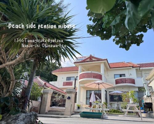a house with a palm tree in front of it at ビーチサイドペンションみーばる in Nanjo