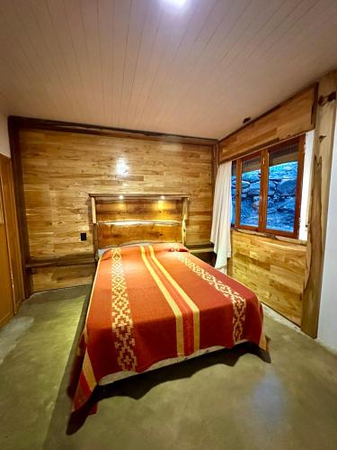 a bedroom with a bed in a room with wooden walls at Casa del lago in Embalse
