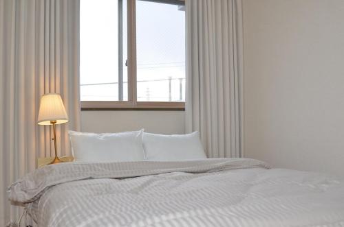a bedroom with a white bed with a window at Cozy Family Room in Matsumoto 201 in Matsumoto