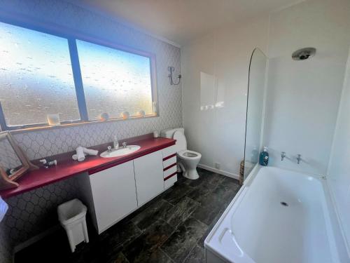 a bathroom with a sink and a tub and a toilet at Cosy Corner Te Anau in Te Anau