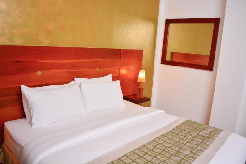 a bedroom with a large white bed and a mirror at Unique Towers Luxury Boutique Suites in Colombo