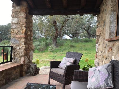 a patio with two chairs and a stone wall at Apartamentos Rurales La Macera **** in Valencia de Alcántara