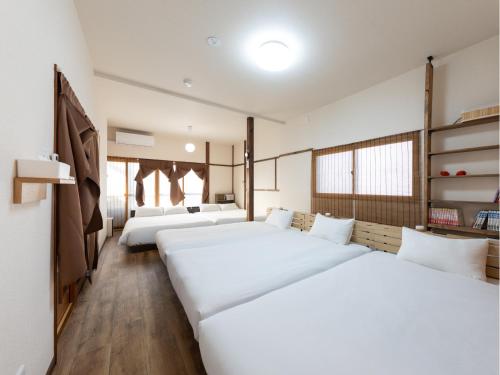 two beds in a room with white walls and wooden floors at Kamenoya, 羽田空港&ディズニー直通バス,2トイレ,亀有駅徒歩7分 in Tokyo