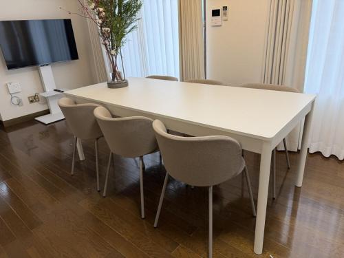 a white table with chairs and a tv in a room at Cozy Family Room 305 in Matsumoto
