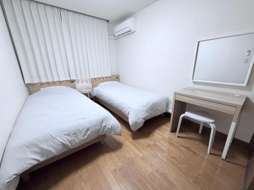 a room with two beds and a desk with a television at Cozy Family Room 305 in Matsumoto