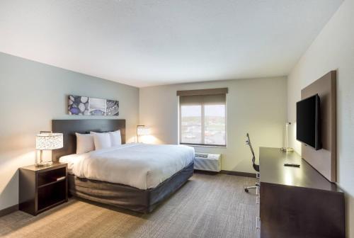 a hotel room with a bed and a flat screen tv at MainStay Suites Logan Ohio-Hocking Hills in Logan