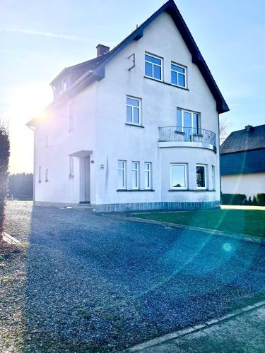 a large white house with the sun shining on it at Ferienhaus Zum Brand in Butgenbach