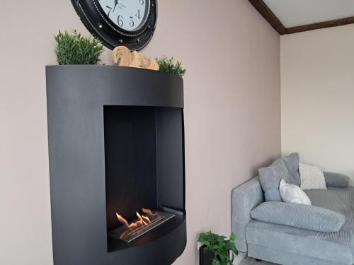 a fireplace in a room with a chair and a clock at Premium StudioApartment in Borovets Gardens in Borovets