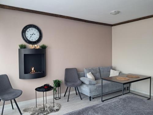 a living room with a couch and a clock on the wall at Premium StudioApartment in Borovets Gardens in Borovets