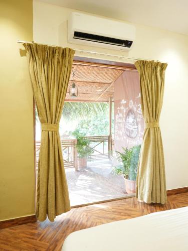 a bedroom with a large window with curtains at Tamarind Retreat in Alibaug