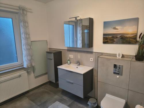 a bathroom with a sink and a toilet and a mirror at Ferienwohnung Wiebe in Minden